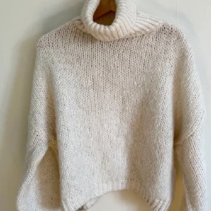 Vit stickad polotröja från Dilvin - Mysig vit stickad polotröja från Dilvin. Perfekt för kyliga dagar med sin höga krage och långa ärmar. Tröjan har en avslappnad passform och är tillverkad i Turkiet. Ett måste för garderoben!