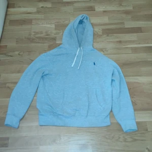 Grå hoodie från Ralph Lauren - Säljer en stilren grå hoodie från Ralph Lauren med en klassisk passform. Den har en justerbar huva med snören och en liten broderad logga på bröstet. Perfekt för en avslappnad look. 