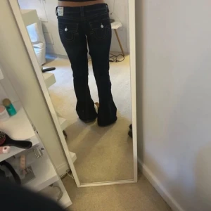 Mörkblå jeans från True Religion - Snygga mörkblå jeans från True Religion med bootcut-stil. De har en låg midja och klassiska femficksdetaljer. Perfekta för en avslappnad look.