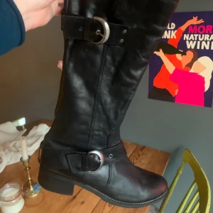 Svarta stövlar med spänne - Snygga svarta stövlar i skinn med dekorativa spännen. Perfekta för höst och vinter. De har en robust klack och rundad tå, vilket ger både stil och komfort. Väldigt bra kvalite, i naturläder! Passar 41 (och 42)