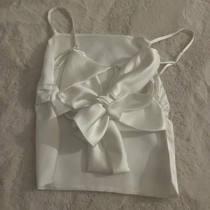 Vit satinlinne med rosett - Vitt satinlinne med smala axelband och knytning där bak med öppen rygg. Endast använd 2/3 gånger 💞