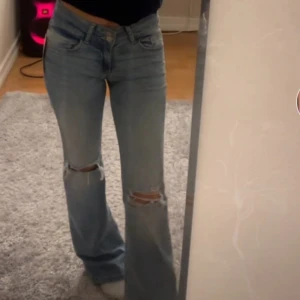 Blå bootcut jeans från Nelly - Snygga blå bootcut jeans från Nelly med slitna detaljer på knäna. Perfekt för en avslappnad stil. De har en klassisk femficksdesign och är tillverkade i jeansmaterial. Betalning vis Swish 