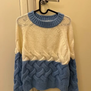 Stickad tröja från MNG Basics - Säljer en mysig stickad tröja från MNG Basics i krämvitt och ljusblått. Tröjan har en bred ribbad krage och ett snyggt flätmönster på den nedre delen. Perfekt för kyliga dagar!