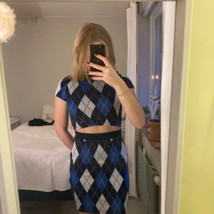 Blå och svart rutig klänning - Snygg klänning med blått och svart rutmönster. Den har korta ärmar och en croppad toppdel som ger en modern look. Perfekt för en trendig outfit. Har en lika dan i S! En för 90kr två för 170kr. Nypris 200kr köpt på rabatt och är oandvända, lapp sitter kvar