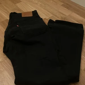 Svarta jeans från Levi's - Snygga svarta jeans från Levi's med klassisk design. Perfekta för en stilren look. De har en rak passform och är tillverkade i ett slitstarkt material.
