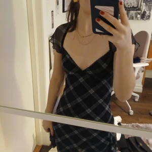 Svart och vit rutig klänning från Hm divided - Snygg svart och vit rutig klänning från Hm med korta ärmar och en v-ringad design. Klänningen har ett figurnära snitt och har en sött rosett på vi v-ringen💕
