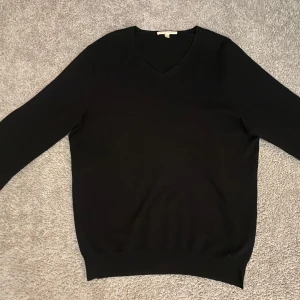 Svart kashmirtröja med v-ringning - Elegant svart kashmirtröja med v-ringning. Perfekt för en stilren look och mjuk komfort. Långärmad design som passar bra till både jeans och kostymbyxor. Den är i nyskick och har aldrig använts.