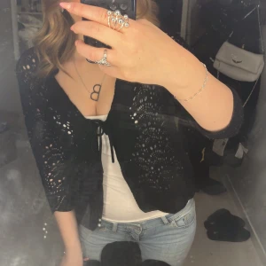 Svart spetskofta - Snygg svart kofta med spetsdetaljer och knytning framtill. Perfekt för att lägga till en elegant touch till din outfit. Passar bra över en enkel topp eller klänning. Storleken är 44/42 men passar mig med xs/s superbra💘