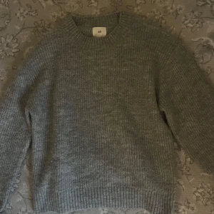 Grå stickad tröja från H&M - Mysig grå stickad tröja från H&M i storlek XS. Perfekt för kyliga dagar med sin ribbade design och långa ärmar. Enkel och stilren, passar till det mesta i garderoben.
