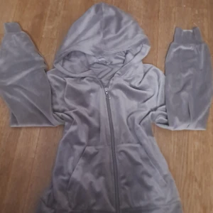 Grå hoodie med dragkedja från 157 - Mysig grå hoodie från 157 i mjukt material med dragkedja och huva. Perfekt för en avslappnad stil. Den har långa ärmar och en praktisk ficka framtill.
