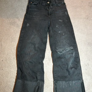 Svarta jeans från Zara - Säljer ett par svarta jeans från Zara i storlek 10. De har en loose passform med slitna detaljer och fransar vid bensluten. Perfekta för en avslappnad stil.
