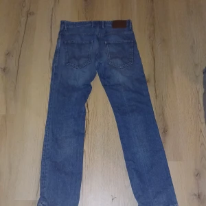 Blå jeansbyxor - Säljer ett par klassiska blå jeansbyxor med rak passform. De har fem fickor och en knappgylf. Perfekta för en avslappnad stil.