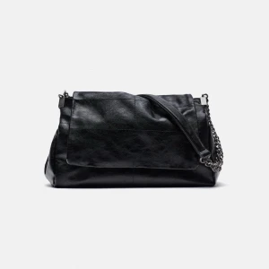 Svart axelväska med kedjedetalj - Snygg svart axelväska i skinn med en cool kedjedetalj på axelremmen. Väskan har en stilren design och är perfekt för att bära dina dagliga nödvändigheter. Den har en praktisk dragkedja för säker förvaring.