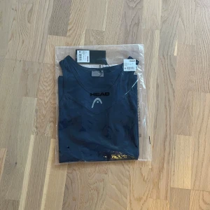 Mörkblå T-shirt/tanktop  från Head - Dam - Säljer en mörkblå dam tanktop tshirt från Head, perfekt för träning. Toppen är ärmlös och har en stilren design med logotypen tryckt på framsidan. Den är tillverkad i ett lätt och bekvämt material. Helt ny och nypris ligger på ca 450kr