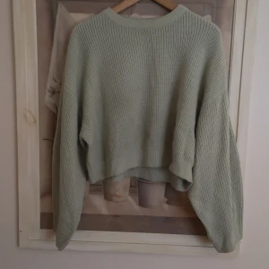 Grön stickad tröja från H&M  - Säljer en mysig grön stickad tröja från H&M Divided. Tröjan har en croppad design med långa ärmar och en rund halsringning. Perfekt för kyliga dagar! (den är i storlek L men den känns mindre) 