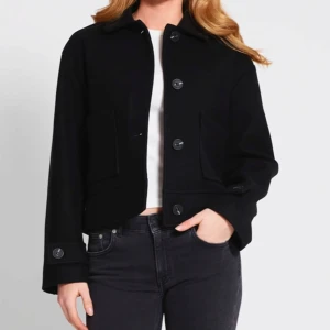 Svart kappa - Snygg svart kappa med stora knappar framtill och två fickor. 