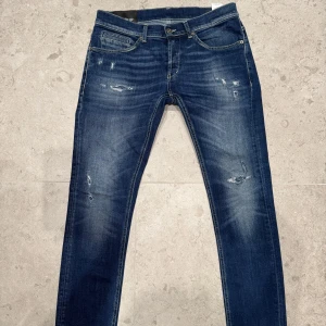 Mörkblåa Dondup jeans med slitningar. - Säljer ett par Dondup jeans i storlek 33. Dem är mörkblåa med lite ljusblåa detaljer. Modellen är George slimfit. Skicket är 9,5/10 då jag knappast har använt dem. Snygga slitningar som ger dem en trendig look. Dem är perfekt till både vardag samt fäst om man vill lyxa till det. Hör av dig om du är intresserad!😀