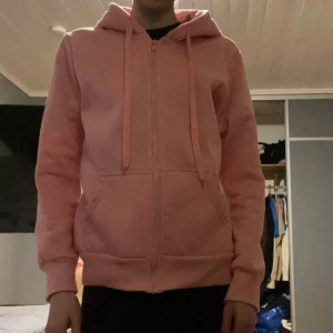 Rosa zip hoodie - Säljer en simpel jättevacker zip hoodie som passar till exakt allting😻Mysig att ha hemma eller när du är ute💋Insidan är ett mjukt fleece liknande tyg. I bra skick (lite nopprig, sista bilden), annars inga fel☺️Så vacker färg!! Hör av dig om du undrar över nått❤️