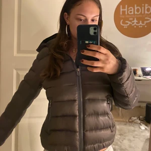 Brun dunjacka från Colmar - Säljer en brun dunjacka från Colmar. passar s/m, har en deffekt som visas på bild tre, det är ett igensytthål, funkar helt normalt. 