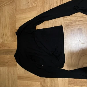 Svart långärmad topp från Gina Tricot - Snygg svart långärmad topp från Gina Tricot. Perfekt för en stilren look. Passar till många olika outfits och tillfällen.
