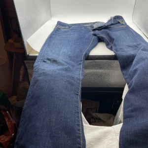 Blå jeans från Replay - Snygga blå jeans från Replay med klassisk femficksdesign och knappgylf. Perfekta för en avslappnad stil med en touch av elegans. Märkesdetaljer på bakfickan och insidan av linningen. L 32 W 33
