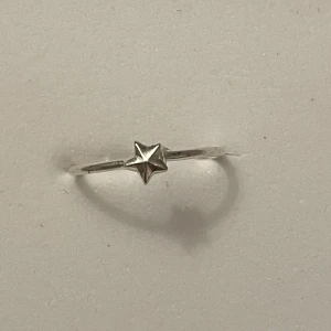 Silverring med stjärndetalj - Elegant och minimalistisk silverring med en liten stjärna som detalj. Perfekt för att lägga till en subtil touch av stil till din look. Ringen är tunn och smidig, vilket gör den bekväm att bära varje dag. Storlek :10mm 