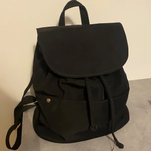 Svart ryggsäck från Even&Odd - Snygg och praktisk svart ryggsäck från Even&Odd. Den har en stilren design med ett stort huvudfack och en innerficka med dragkedja Ryggsäcken har justerbara axelremmar och stängs med en dragsko och lock. Perfekt för vardagsbruk!