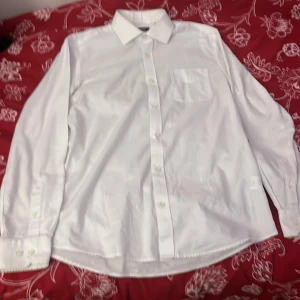 Vit skjorta från Dressmann - Klassisk vit skjorta från Dressmann i storlek M. Skjortan har en bröstficka och knappar framtill. Perfekt för en stilren look.
