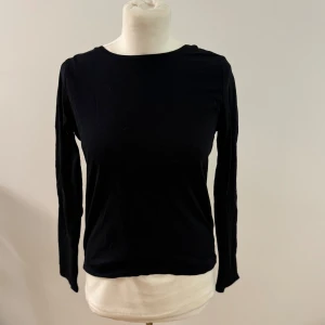 Svart långärmad topp med öppen rygg från NA-KD - Säljer en stilren svart långärmad topp från NA-KD i storlek XS. Den har en snygg öppen rygg som ger en extra touch till outfiten. Perfekt för både vardag och fest! 🖤