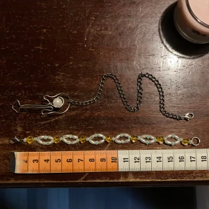 Armband med gitarr och pärlor - Säljer tvp unika egnengjorda armband 50kr/st, en med en cool gitarrdesign i silverfärg och en stor pärla. Armbandet har också en kedja med vita och gula pärlor som ger en färgglad touch. Perfekt för musikälskare eller som ett statement-smycke! 