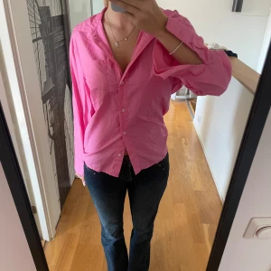Rosa skjorta med knappar - Säljer en snygg rosa skjorta med knappar framtill. Skjortan har en avslappnad passform och långa ärmar som kan rullas upp för en mer casual look. Perfekt för både vardag och festliga tillfällen!