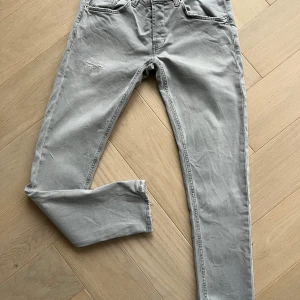 Grå jeansbyxor - Säljer ett par grå jeansbyxor i en klassisk stil skinny fit model RITCHIE stl 33 . Byxorna har fem fickor och knapp gylf framtill. Perfekta för vardagsbruk!