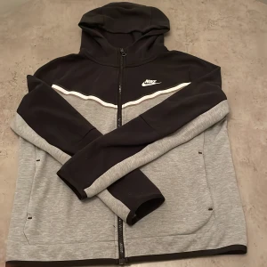 Grå och svart hoodie från Nike - Säljer nu min nike tech som är för liten för mig. Det finns inga fläckar och den är inte sliten.