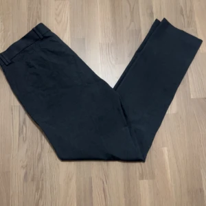 Svarta kostymbyxor från River Island - Säljer ett par stilrena svarta kostymbyxor från River Island. De är högmidjade och har en rak passform som ger en klassisk look. Riktigt snygga gråa, syns inte så bra på bild. Nypris 399kr. Mitt pris 99kr.