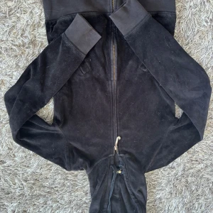 Svart hoodie från Juicy Couture - ⚠️igga att bilderna är upponer  ⚠️Säljer en svart hoodie från Juicy Couture i storlek XS. Den är gjord av mjuk velour och har en glittrig dragkedja framtill. Perfekt för en avslappnad och stilren look. Hoodien har långa ärmar och ribbade muddar.