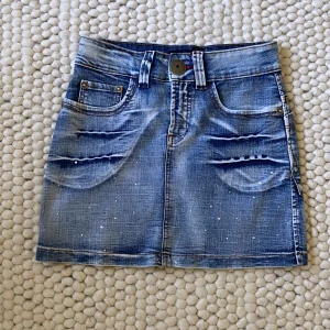 Lågmidjad jeanskjol - Midja: 34 cm rakt över (68 cm runt hela)💕 Längd: ca 34-35 cm mitt på⭐️ Obs! En diamant har lossnat se sista bild, med det märks absolut inte💕 Tryck gärna på köp nu eller ge ett prisförslag⭐️ (För liten för mig så kan inte ta några bilder med kjolen på)