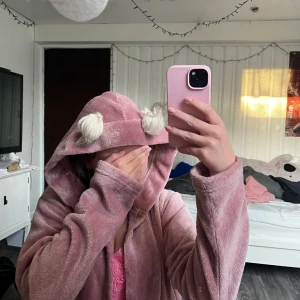 Rosa Morgonrock - Rosa morgonrock med två små söta tussar vid huvan. Storlek 170. I bra skick.  Alla kläder tvättas innan dem skickas!