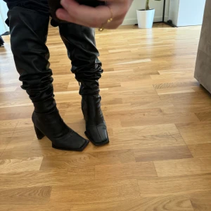 Svarta stövlar med klack - Säljer ett par snygga Na-kd svarta stövlar i skinn med klack. De har en spetsig tå och en stilren design som passar perfekt för höst och vinter. Stövlarna har en dragkedja på insidan för enkel på- och avtagning.
