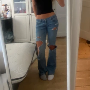 Lågmidjade utsvängda jeans med så snygga hål  - Säljer dehär supersnygga lågmidjade utsvängda jeansen med så snygga hål. De är lite slitna längst nere vid fötterna men inget som märks mycke.💕midjemåttet: 38cm, innerbenslängden: 83cm. W:26 L:33. Skulle säga att de är ungefär S