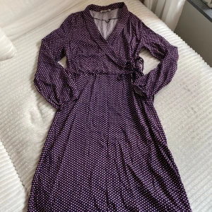 Mönstrad klänning i blått och rött med snörning i midjan - Jättefin mönstrad klänning i blått och rött. Knyt vid sidan. Fin till hösten. Mycket fint skick! Storlek 38! 