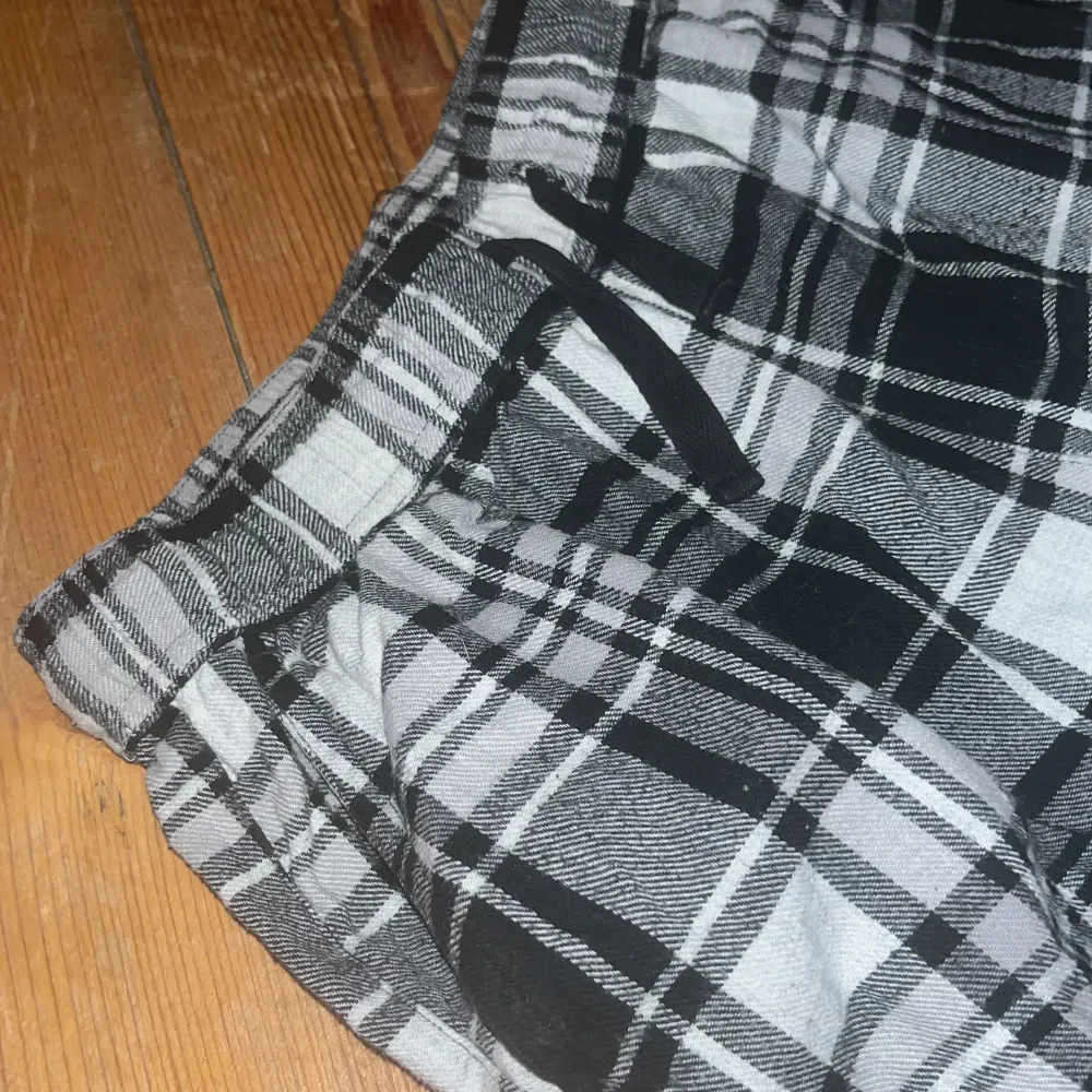 Säljer ett par bekväma och stiliga rutiga byxor från Kappahl. Byxorna har en elastisk midja med snörning och är perfekta för en avslappnad look. De är i svart, grått och vitt med ett klassiskt rutmönster. Nästan aldrig använda. Säljer pga-för små! Kontakta för mer information!!!. Farkut & Housut.