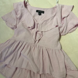 Ljusrosa blus från Primark - Söt ljusrosa blus från Primark med volangdetaljer och korta ärmar. Perfekt för en somrig look med sin luftiga design och mjuka material. Storlek L men passar mig som är S.