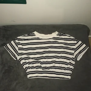 Randig croppad topp från Lefties - Säljer en snygg randig croppad topp från Lefties i svart och vit. Toppen har korta ärmar och en elastisk midja för en bekväm passform. Perfekt för sommaren!🌊☀️⛱