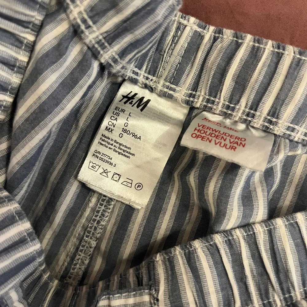 Säljer ett par bekväma randiga byxor från H&M i blått och vitt. Byxorna har en elastisk midja med snörning för extra komfort. Perfekta för en avslappnad stil.. Farkut & Housut.