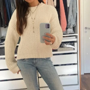 Vit stickad tröja från Zara - Säljer en mysig beige stickad tröja med rund hals och långa ärmar. Perfekt för kyliga dagar och lätt att matcha med jeans eller kjol. Enkelt och stilrent plagg för garderoben.