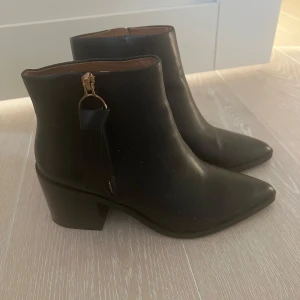 Svarta stövletter med dragkedja - Snygga svarta stövletter med klack och spetsig tå. De har en praktisk dragkedja på sidan för enkel på- och avtagning. Perfekta för både vardag och festliga tillfällen. Från & Other stories. Endast använda 2 tillfällen!