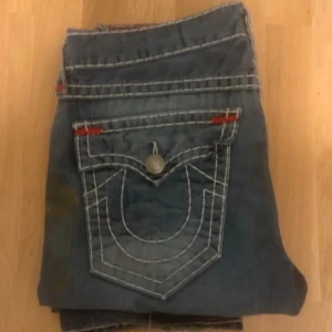 Feta true religion byxor med fat stitch - Galna truey jeans med slitningar och paintsplatter som ska vara där och är originellt. Dem är fat stitch vilket gör priset dyrare. Det står storlek 36 men passar mig perfekt som brukar ha 32 i midjan. De har en bootcut/baggy fit. Köpta från vintage and friends kan rekomendera väldigt mycket!  Skriv om ni har frågor eller om ni vill ha fler bilder!!!