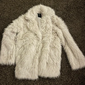 Vit pälsjacka - Säljer en fluffig och stilren nästan oanvänd pälsjacka med långärmad design från lager 157. Är i storlek xs/s