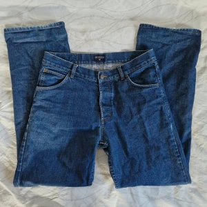 Vintagejeans från Cottonfield - Säljer ett par blå vintagejeans från Cottonfield. Storlek W33, L32. De har en straight passform och stängs med knappar. Köpta second hand, i superfint skick bortsett från osynlig slitning längst ned på ena benet. Fler bilder kan skickas och pris är diskuterbart! :)