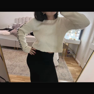Vit ribbad tröja från Calvin Klein - Säljer en snygg vit ribbad tröja från Calvin Klein med text längs ärmen. Tröjan är croppad och har långa ärmar, perfekt för en stilren look. Passar bra till både jeans och kjol! Storlek L men passar som S/M